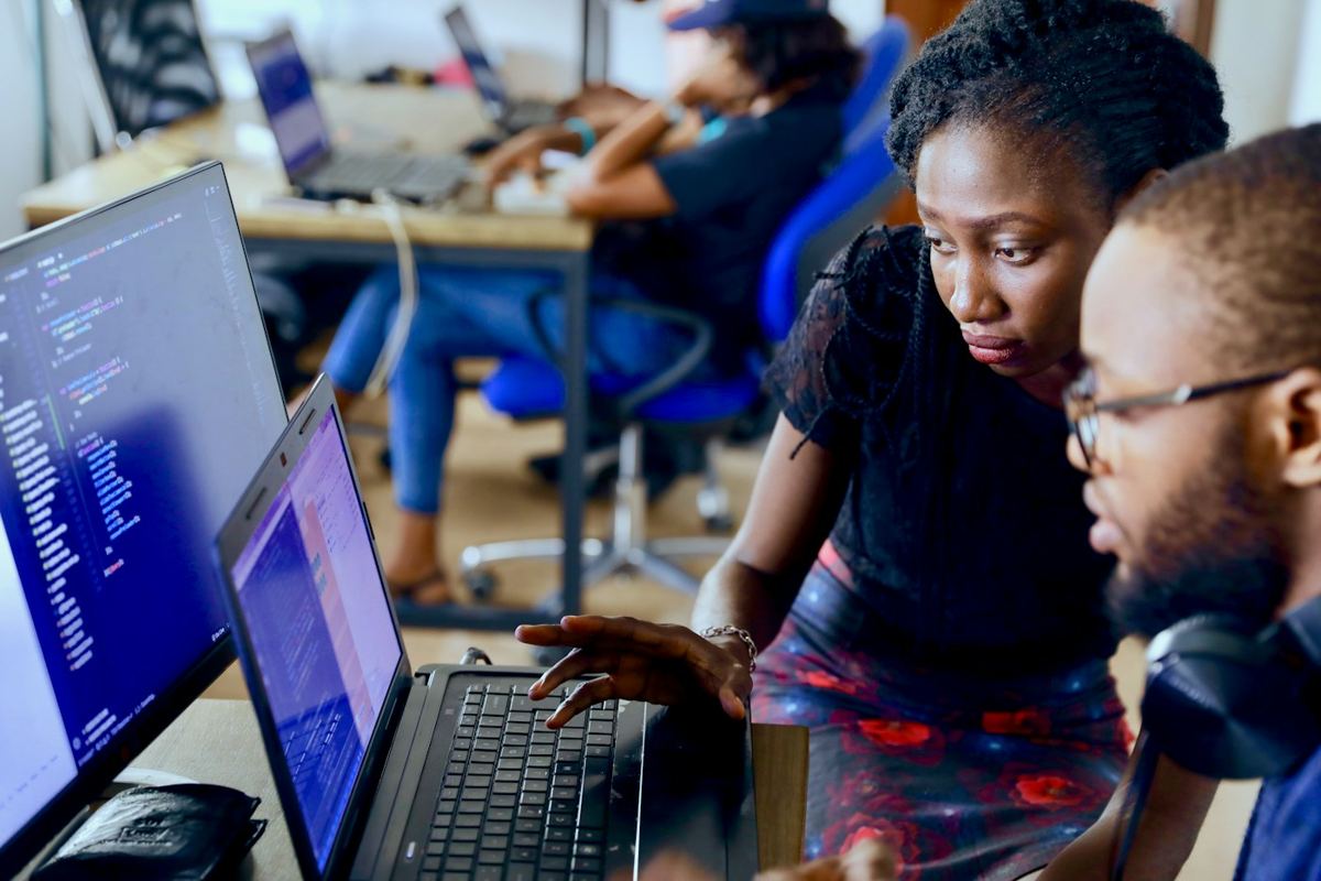 Young people working together at laptops in a tech workspace