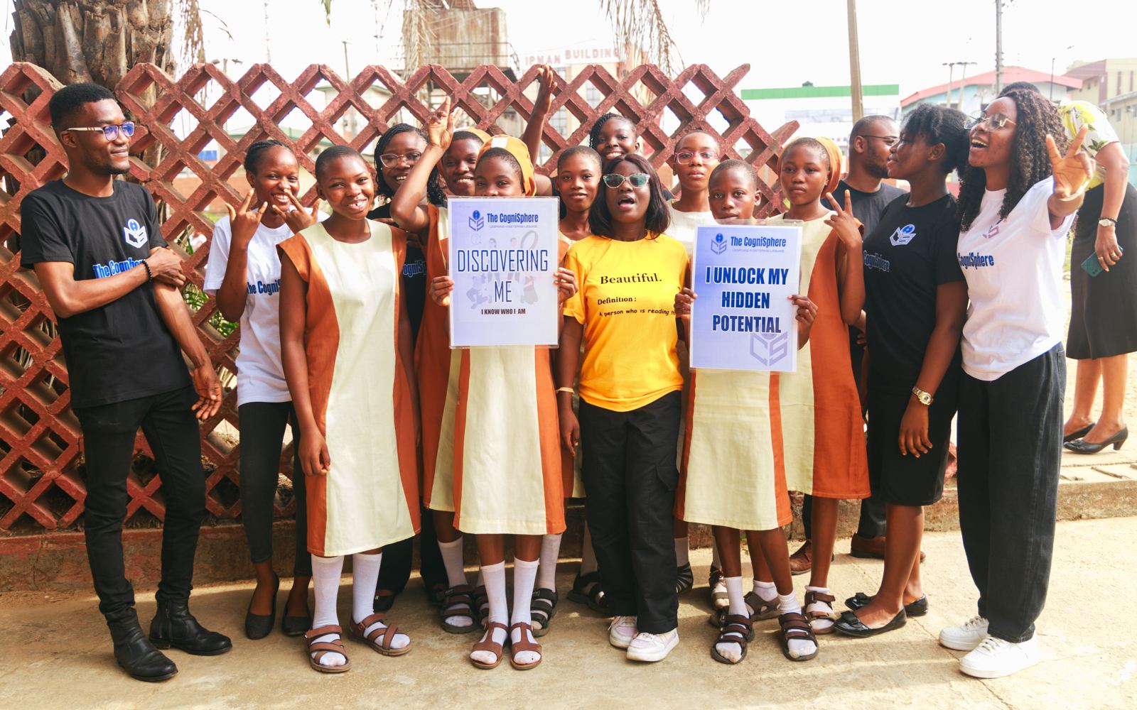 Students and volunteers pose together holding Discovering Me signs
