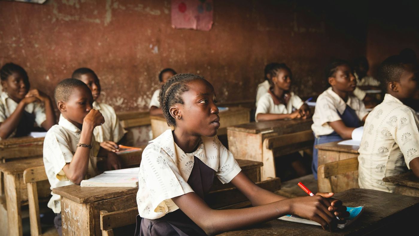 Secondary school students in uniform sitting at wooden desks in a Lagos classroom