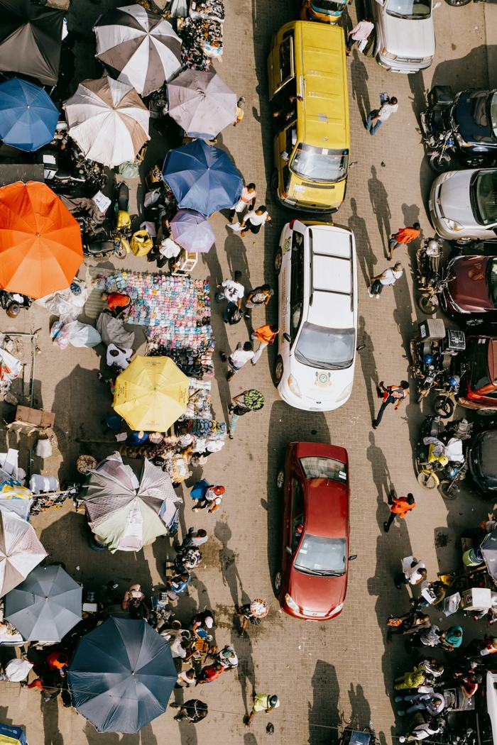 Aerial view of a busy Lagos street market with colourful umbrellas and traffic